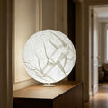 Large glowing paper moon sphere lamp on a console in a warm hallway