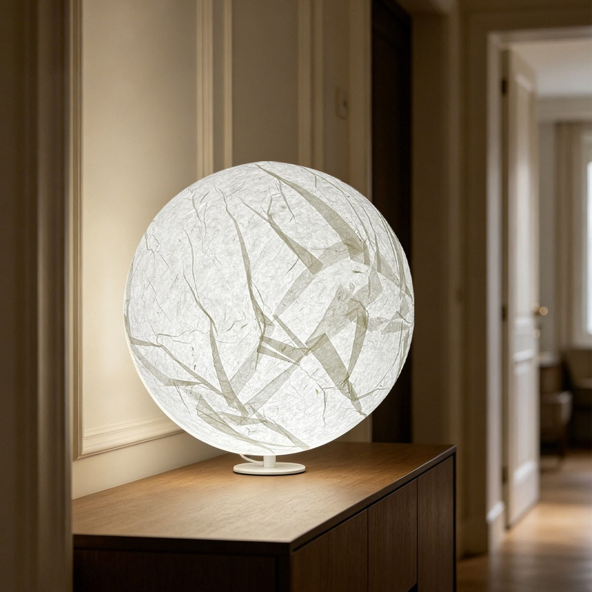 Large glowing paper moon sphere lamp on a console in a warm hallway
