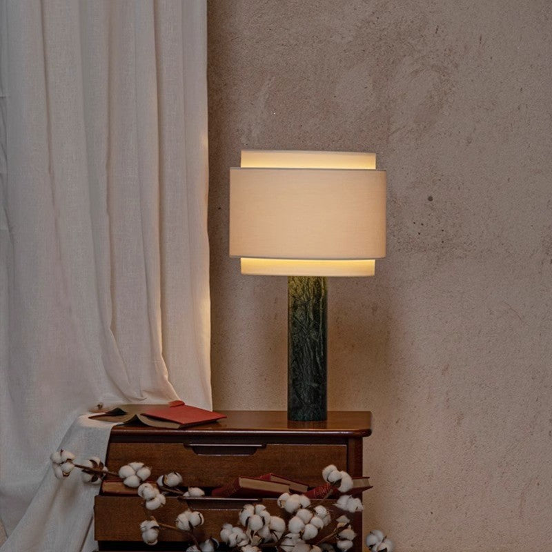Olive green marble column lamp styled on a dark wood side table