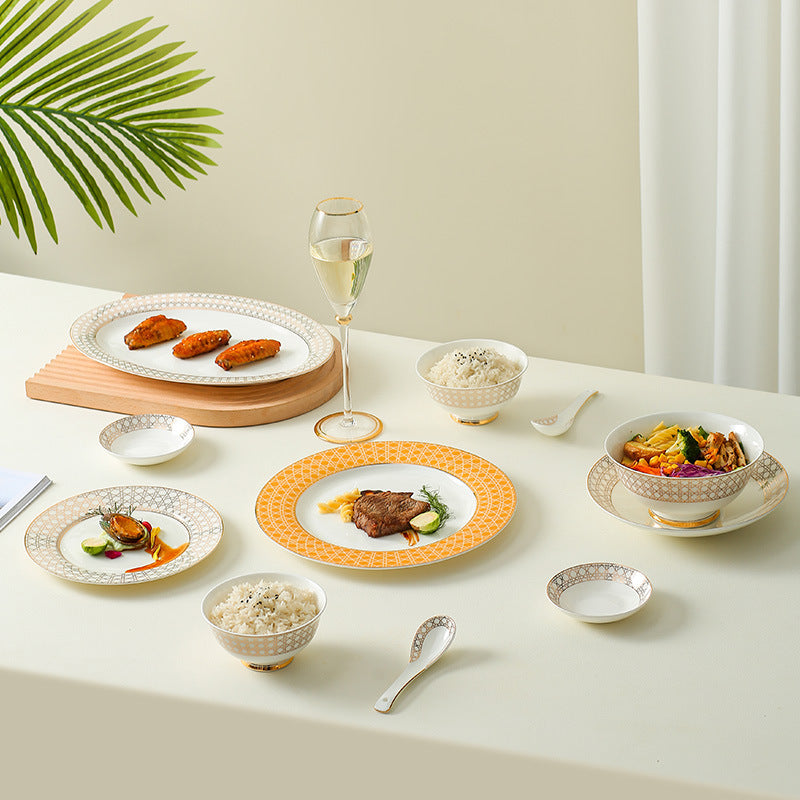 Provence lattice bone china dinner table setting with orange and grey patterned plates, bowls, fish platter and wine glass