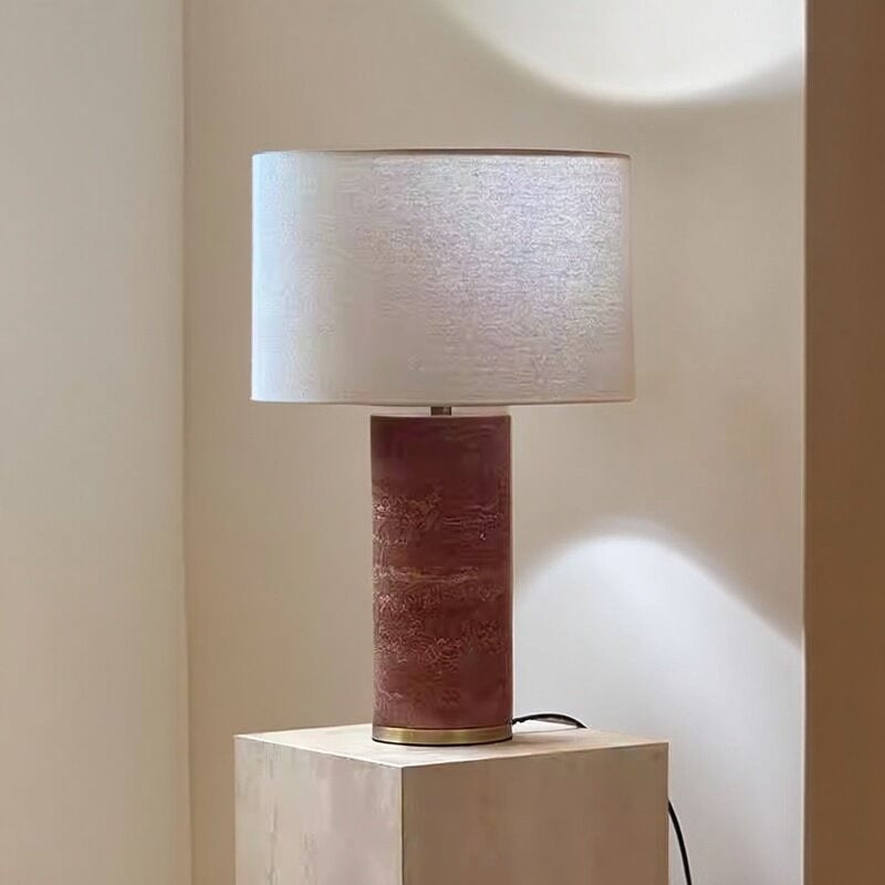 Red travertine column lamp with fabric shade styled on a light stone console