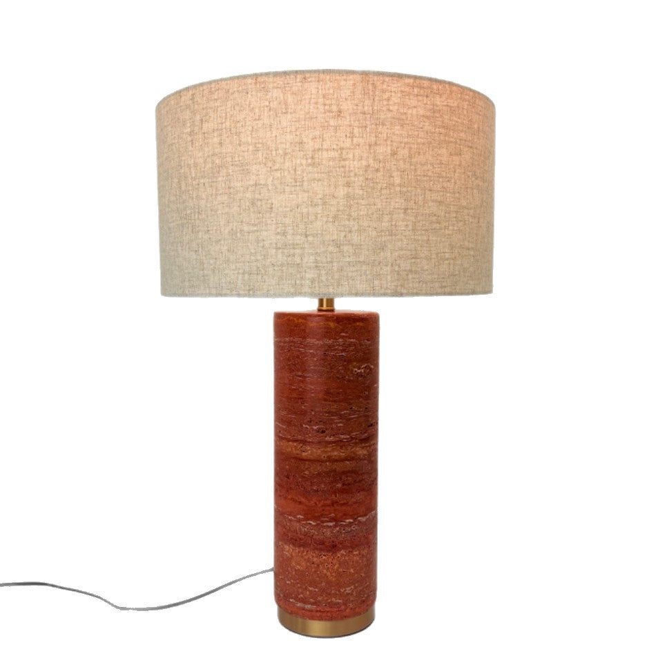 Red travertine cylindrical table lamp with neutral fabric shade on white background