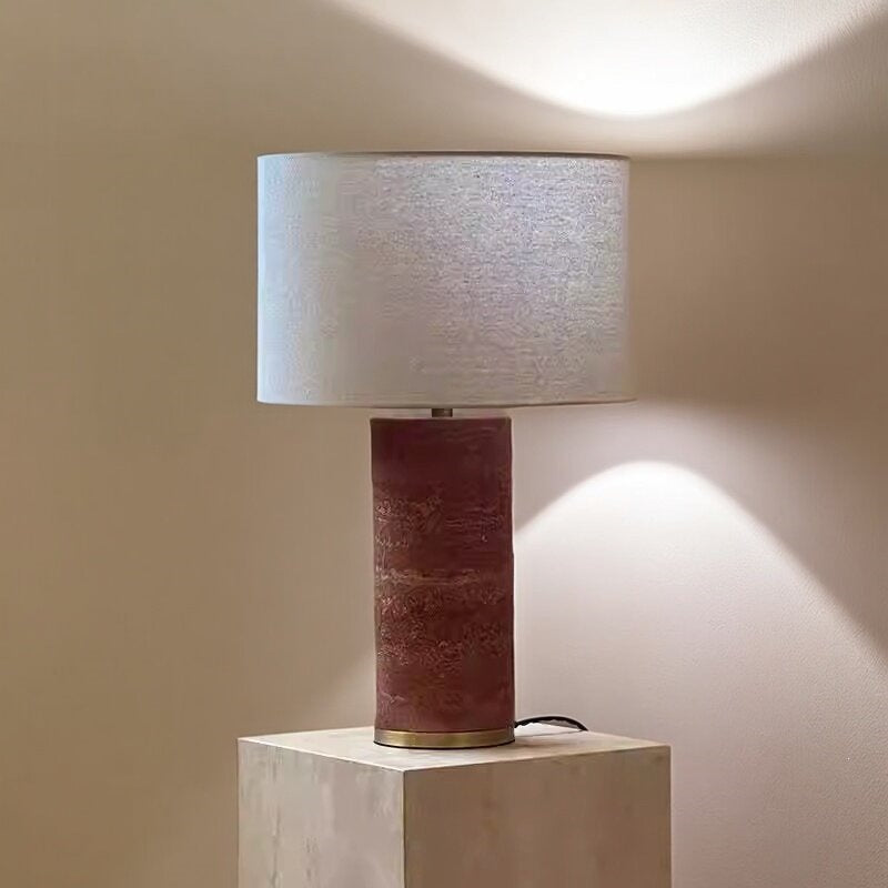Red travertine column table lamp casting warm ambient light against a wall