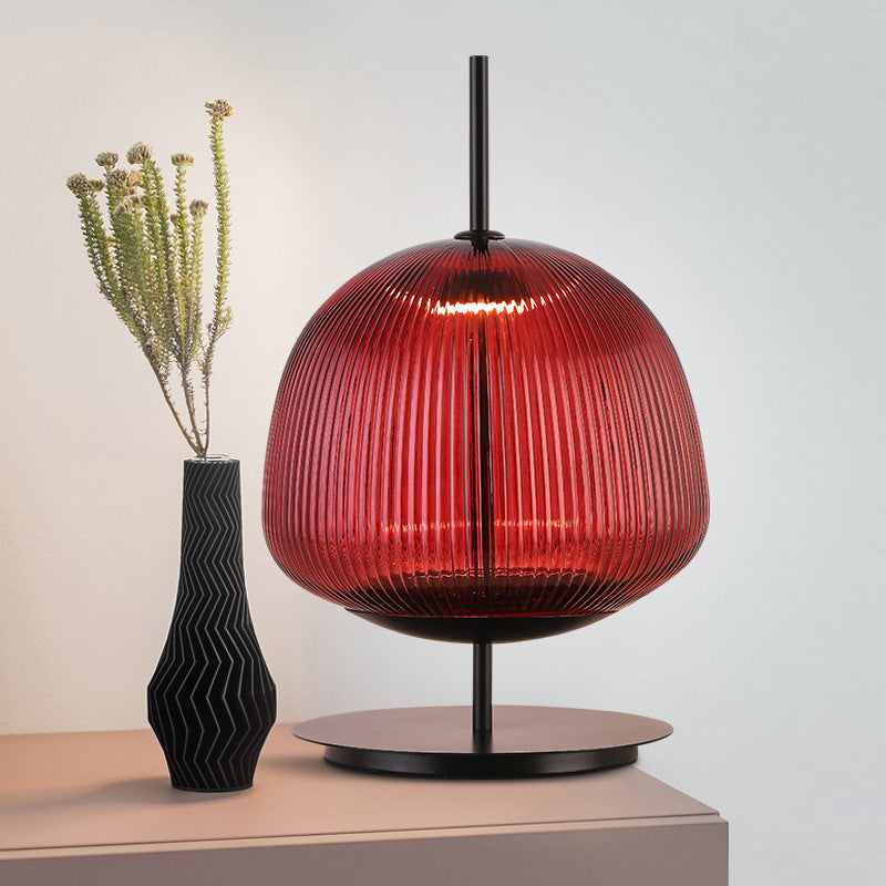 Red ribbed glass lantern table lamp with black metal stand in a contemporary interior