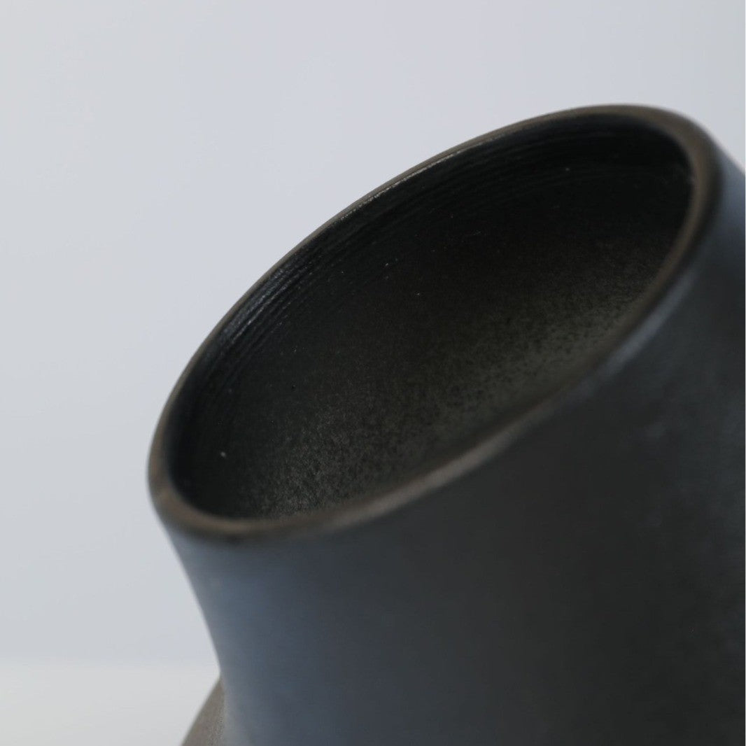 Close detail of black ceramic vase rim and textured finish