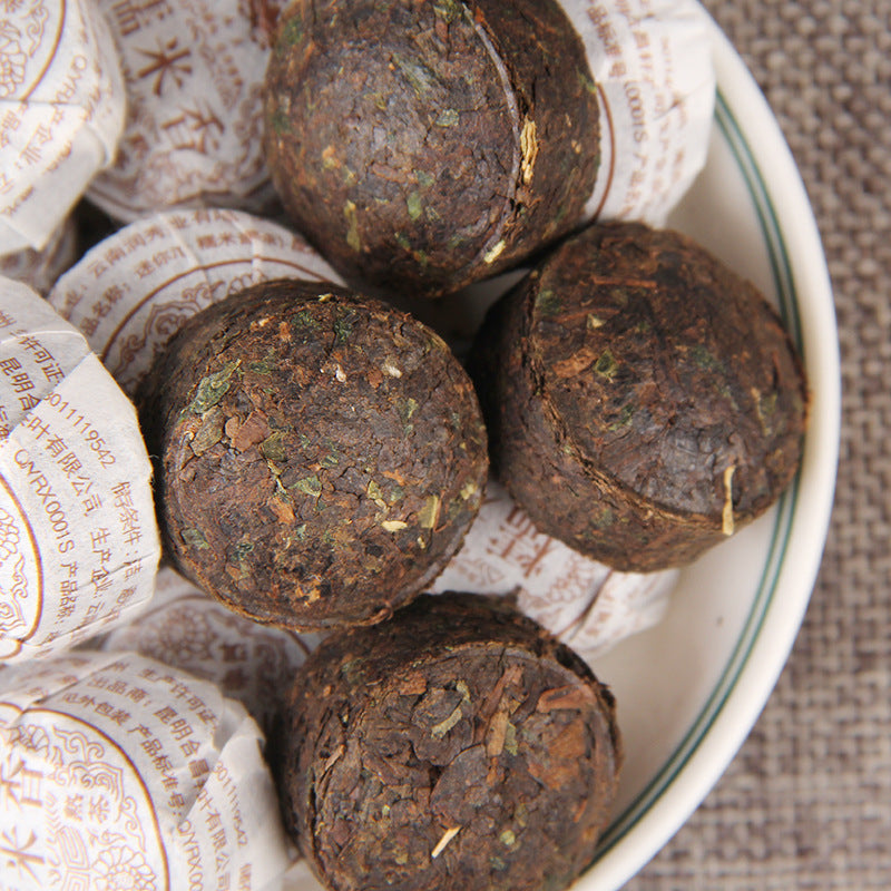 Unwrapped sticky rice aroma ripe Pu-erh mini tuocha showing compressed tea leaves