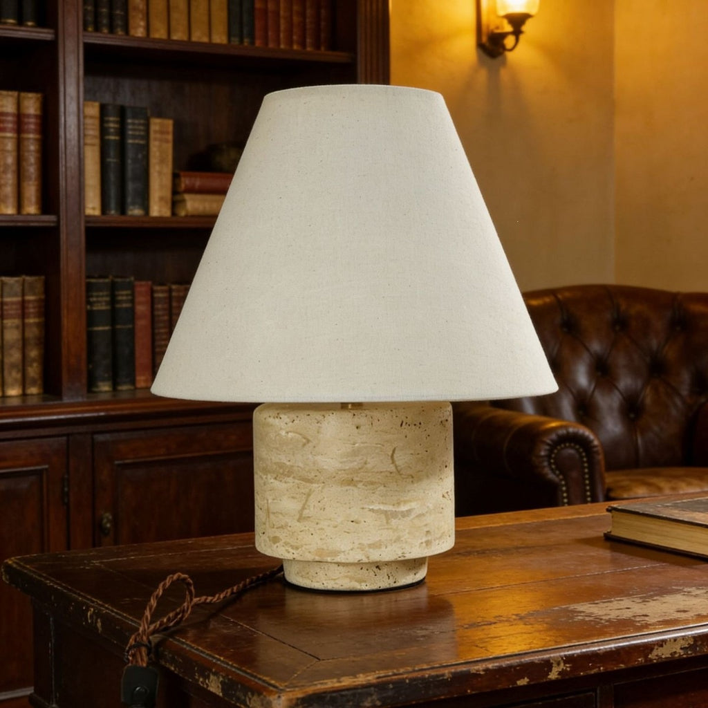 Natural travertine cylinder table lamp with ivory fabric shade in a classic study