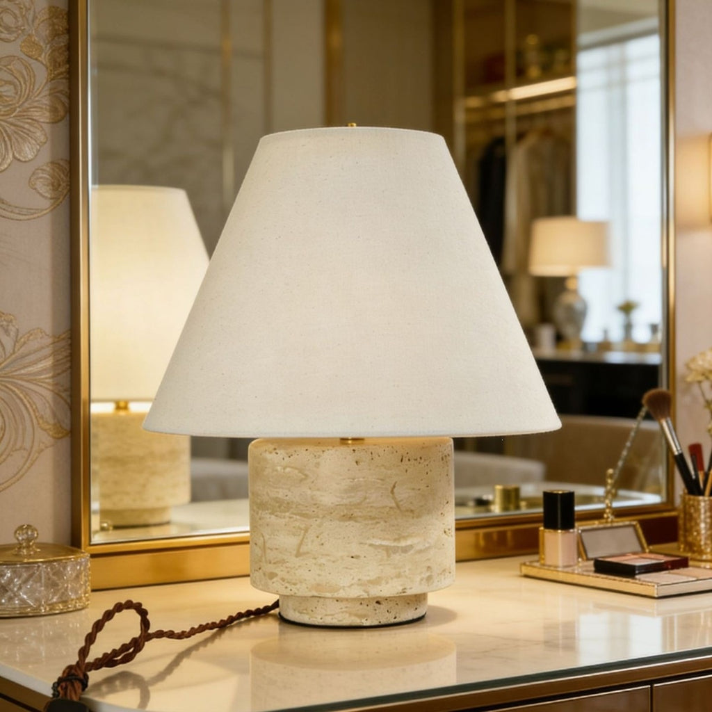 Natural travertine bedside table lamp with tapered cream shade on a mirrored console