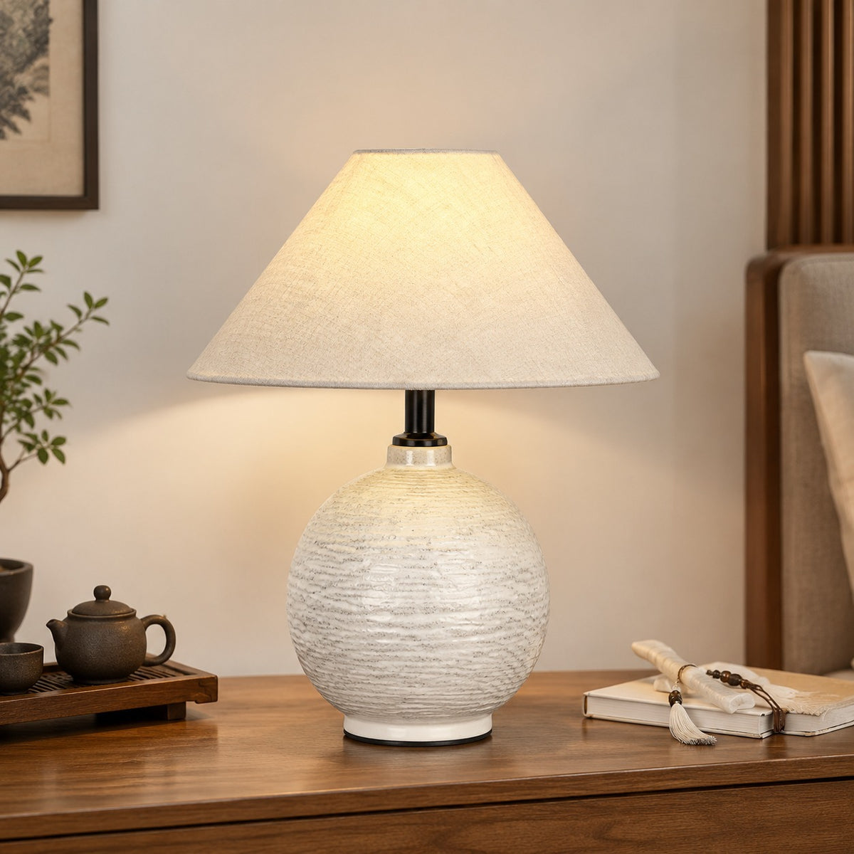 White round ceramic table lamp with cream shade styled beside dark tea ware