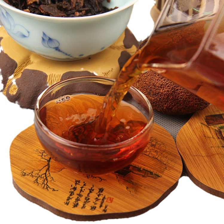 Red amber liquor from Xinhui mandarin ripe Pu-erh tea being poured