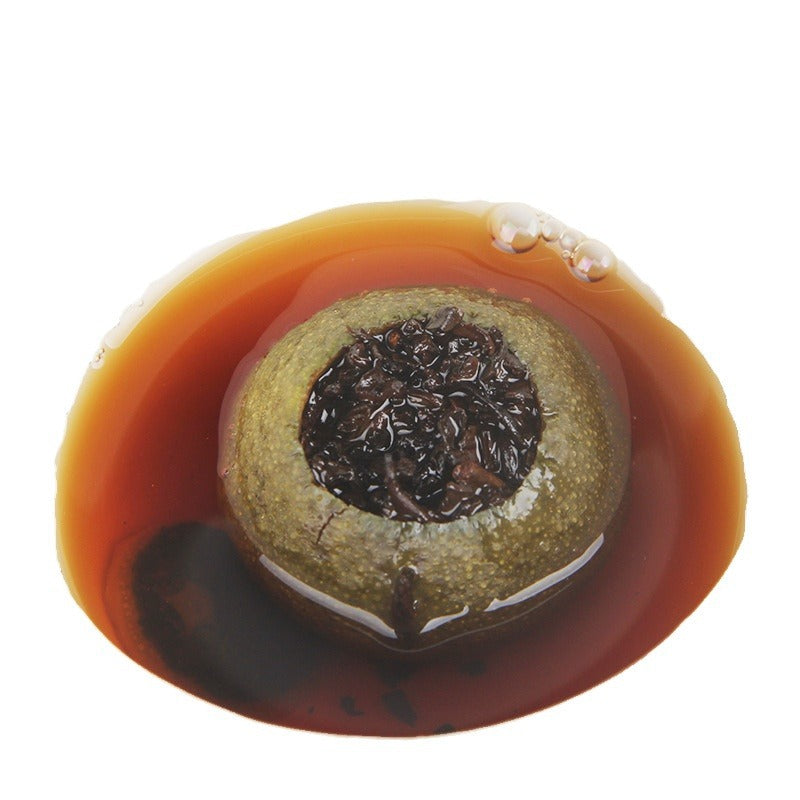 Brewed Xiaoqinggan whole green mandarin Pu-erh in amber-red tea liquor