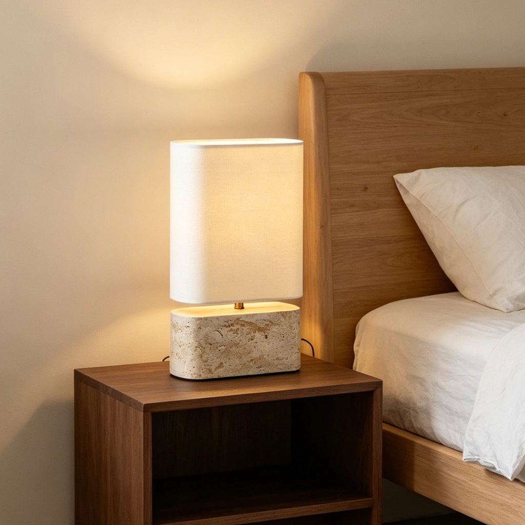 Yellow travertine bedside table lamp glowing warmly against wood headboard